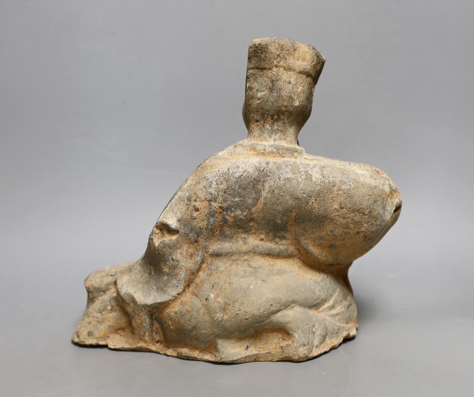 A Chinese grey pottery figure of a seated musician, Han dynasty (200BCE to 220CE) or later, 25cm high